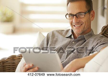 Stock Photo - Portrait of smiling man using digital tablet. Fotosearch