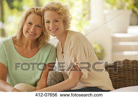 Portrait of smiling mother and daughter on patio View Large Photo Image Stock Photograph - Portrait of smiling mother and daughter on patio. Fotosearch