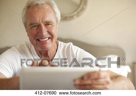 Portrait of smiling senior man using digital tablet in bedroom View Large Photo Image Stock Image - Portrait of smiling senior man using digital tablet in bedroom. Fotosearch