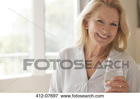 Portrait of smiling woman drinking glass of water View Large Photo Image Stock Photo - Portrait of smiling woman drinking glass of water. Fotosearch