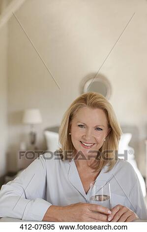 Portrait of smiling woman drinking glass of water in bedroom View Large Photo Image Stock Photography - Portrait of smiling woman drinking glass of water in bedroom. Fotosearch