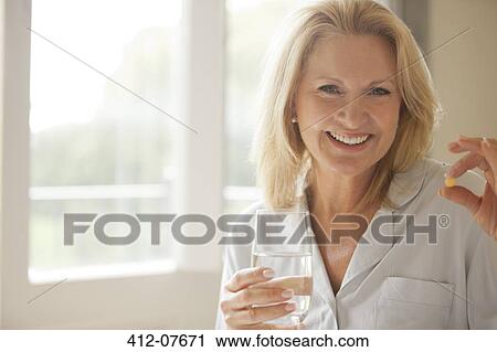 Portrait of smiling woman holding pill and glass of water View Large Photo Image Stock Image - Portrait of smiling woman holding pill and glass of water. Fotosearch