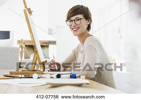 Portrait of smiling woman painting at easel on table View Large Photo Image Stock Photo - Portrait of smiling woman painting at easel on table. Fotosearch