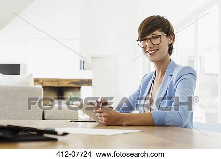 Portrait of smiling woman using digital tablet at table View Large Photo Image Picture - Portrait of smiling woman using digital tablet at table. Fotosearch