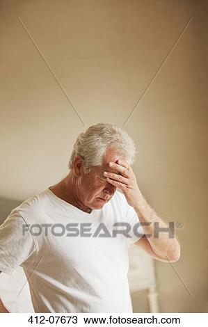 Stock Image - Senior man holding head in pain. Fotosearch