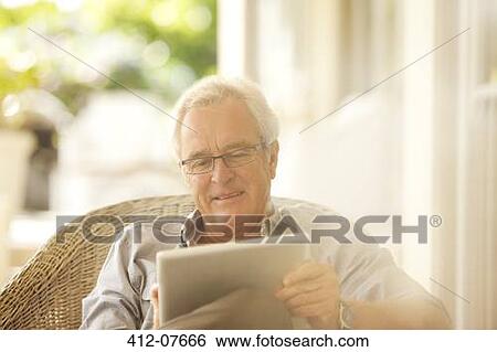 Senior man using digital tablet on patio View Large Photo Image Stock Photograph - Senior man using digital tablet on patio. Fotosearch