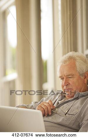 Picture - Serious senior man using laptop. Fotosearch