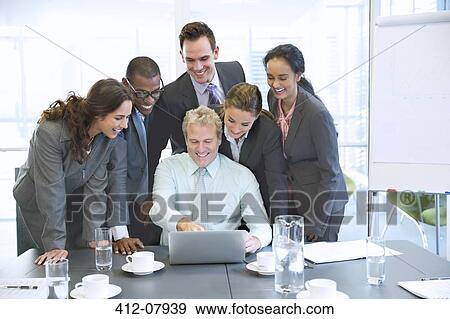 Smiling business people sharing laptop in conference room View Large Photo Image Stock Photo - Smiling business people sharing laptop in conference room. Fotosearch