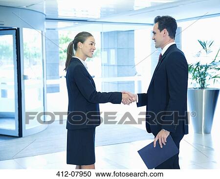 Smiling businessman and businesswoman handshaking in lobby View Large Photo Image Stock Image - Smiling businessman and businesswoman handshaking in lobby. Fotosearch