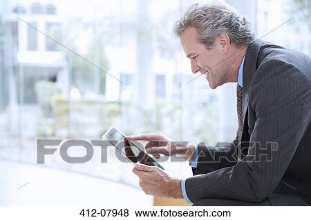 Smiling businessman using digital tablet View Large Photo Image Stock Photo - Smiling businessman using digital tablet. Fotosearch