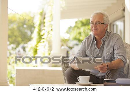 Smiling man using digital tablet on porch View Large Photo Image Stock Image - Smiling man using digital tablet on porch. Fotosearch