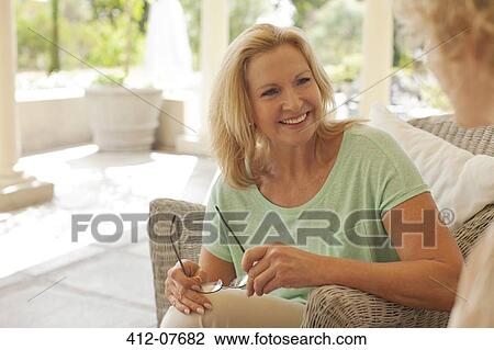 Smiling mother and daughter talking on porch View Large Photo Image Stock Image - Smiling mother and daughter talking on porch. Fotosearch