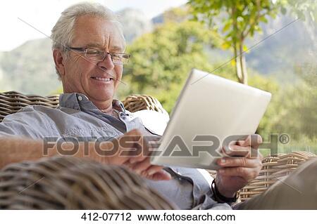 Smiling senior man using digital tablet on patio View Large Photo Image Stock Image - Smiling senior man using digital tablet on patio. Fotosearch