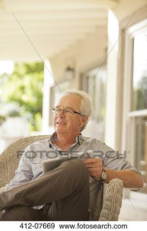 Smiling senior man using digital tablet on porch View Large Photo Image Stock Photo - Smiling senior man using digital tablet on porch. Fotosearch
