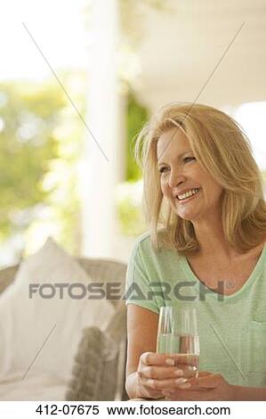 Smiling woman drinking water on patio View Large Photo Image Stock Photography - Smiling woman drinking water on patio. Fotosearch