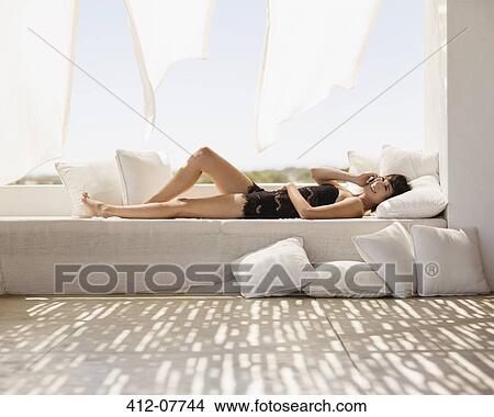 Smiling woman laying on patio sofa talking on cell phone View Large Photo Image Picture - Smiling woman laying on patio sofa talking on cell phone. Fotosearch