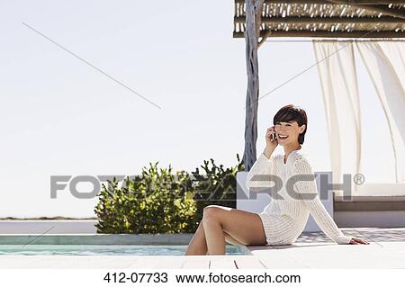 Smiling woman talking on cell phone at poolside View Large Photo Image Stock Image - Smiling woman talking on cell phone at poolside. Fotosearch