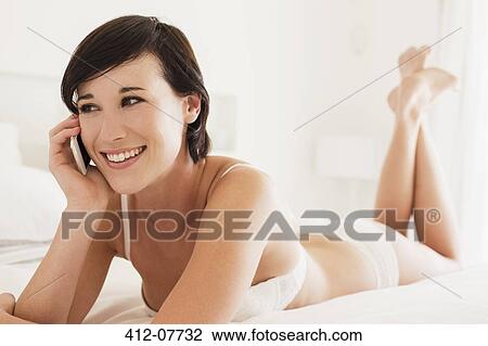 Smiling woman talking on cell phone in bed View Large Photo Image Stock Image - Smiling woman talking on cell phone in bed. Fotosearch
