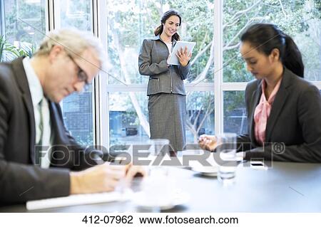Smiling woman using digital tablet at window in conference room View Large Photo Image Stock Image - Smiling woman using digital tablet at window in conference room. Fotosearch