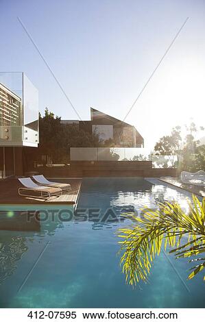 Stock Photography - Sun shining over modern house and swimming pool. Fotosearch