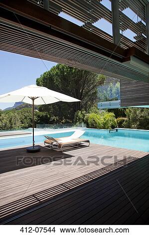 Swimming pool, lounge chair, umbrella View Large Photo Image Picture - Swimming pool, lounge chair, umbrella. Fotosearch