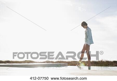 Stock Image - Woman dipping toe in swimming pool. Fotosearch