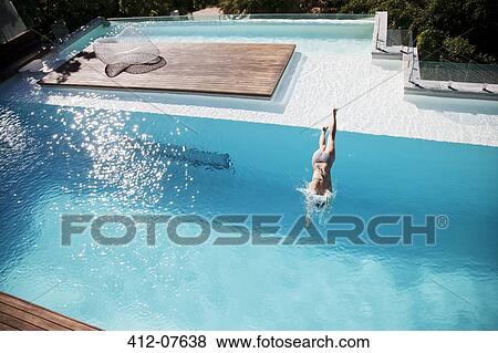Stock Photo - Woman diving in luxury swimming pool. Fotosearch