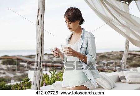 Woman drinking wine and text messaging with cell phone on patio View Large Photo Image Stock Photograph - Woman drinking wine and text messaging with cell phone on patio. Fotosearch