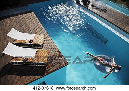Woman floating on inflatable ring in luxury swimming pool View Large Photo Image Stock Photo - Woman floating on inflatable ring in luxury swimming pool. Fotosearch