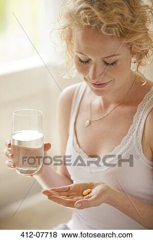 Woman holding glass of water and pills View Large Photo Image Stock Photo - Woman holding glass of water and pills. Fotosearch