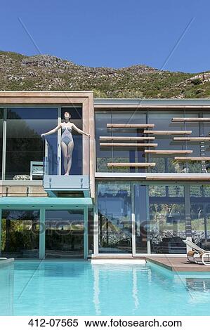 Stock Photography - Woman on balcony above swimming pool. Fotosearch