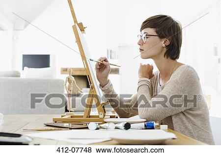 Woman painting on easel at table View Large Photo Image Stock Photo - Woman painting on easel at table. Fotosearch