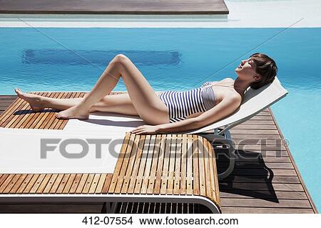 Woman sunbathing at poolside View Large Photo Image Picture - Woman sunbathing at poolside. Fotosearch