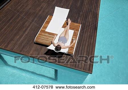Stock Photo - Woman sunbathing at poolside. Fotosearch