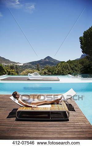 Woman sunbathing at poolside View Large Photo Image Stock Photograph - Woman sunbathing at poolside. Fotosearch