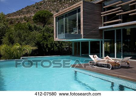 Woman sunbathing on lounge chair at poolside View Large Photo Image Stock Image - Woman sunbathing on lounge chair at poolside. Fotosearch