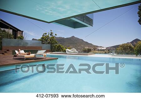 Woman sunbathing on lounge chair at poolside with mountain view View Large Photo Image Stock Image - Woman sunbathing on lounge chair at poolside with mountain view. Fotosearch