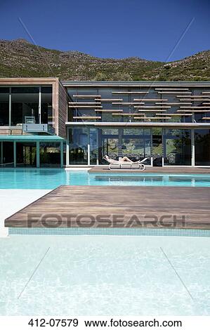 Woman sunbathing poolside of modern house View Large Photo Image Stock Photo - Woman sunbathing poolside of modern house. Fotosearch