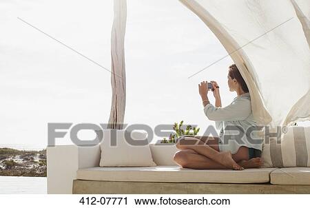 Woman taking photograph on sunny patio View Large Photo Image Stock Image - Woman taking photograph on sunny patio. Fotosearch