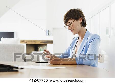 Stock Photography - Woman using digital tablet at table. Fotosearch