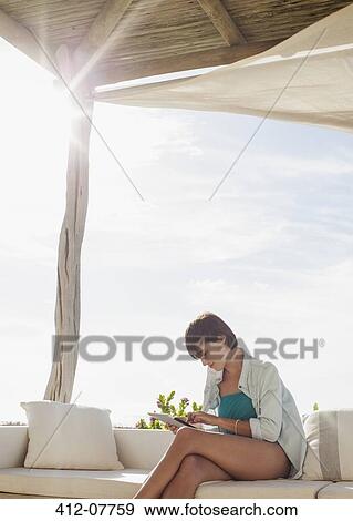 Stock Photo - Woman using digital tablet on sunny patio. Fotosearch