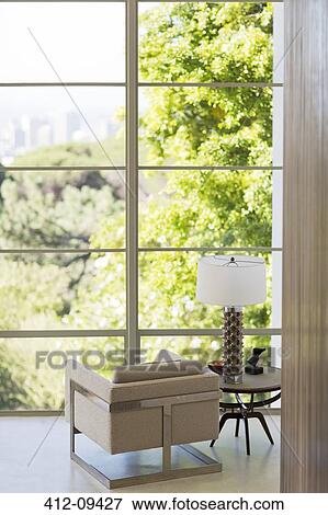 Stock Photo - Armchair in living room overlooking trees to city view. Fotosearch