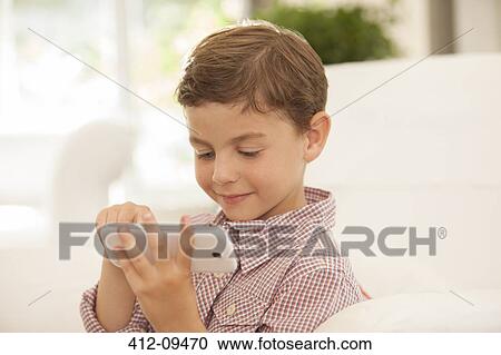 Boy using cell phone on sofa View Large Photo Image Stock Image - Boy using cell phone on sofa. Fotosearch