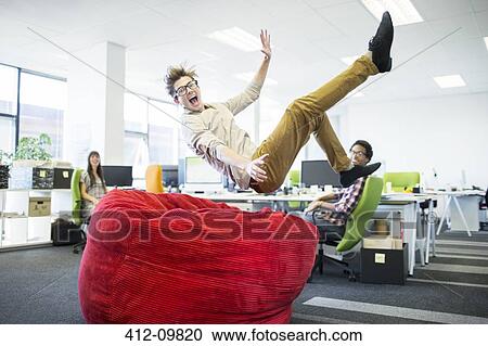 Businessman jumping into beanbag chair in office View Large Photo Image Stock Image - Businessman jumping into beanbag chair in office. Fotosearch