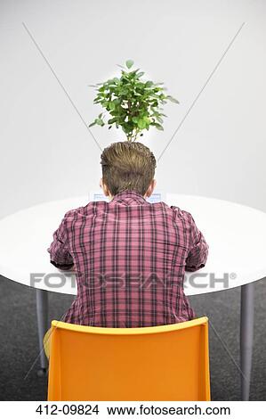 Businessman working at table with plant View Large Photo Image Picture - Businessman working at table with plant. Fotosearch