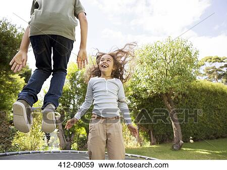 Children jumping on trampoline in backyard View Large Photo Image Stock Photo - Children jumping on trampoline in backyard. Fotosearch