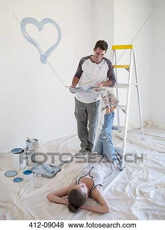 Stock Photo - Couple painting blue heart on wall. Fotosearch