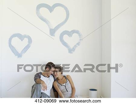 Stock Photo - Couple painting blue hearts on wall. Fotosearch