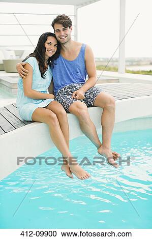 Couple relaxing at edge of swimming pool View Large Photo Image Stock Image - Couple relaxing at edge of swimming pool. Fotosearch
