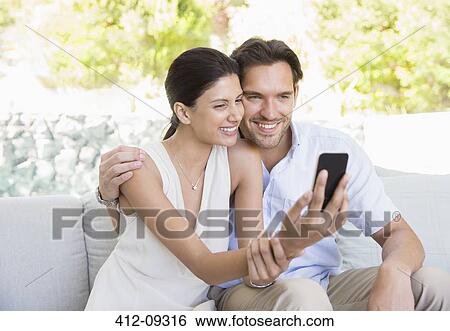 Stock Photograph - Couple taking self-portrait with camera phone. Fotosearch